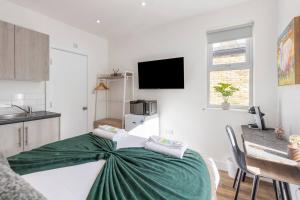 a bedroom with a bed with a green blanket on it at The Best City Studio Near Public Transport in Ealing
