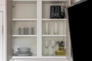 a cabinet with glasses and plates and a microwave at Modern Studio Retreat Near Shop's! in Ealing