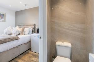 a bathroom with a bed and a toilet in a room at Modern Studio Retreat Near Shop's! in Ealing