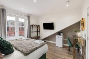 a bedroom with a bed and a desk and a television at Cosy Studio Perfect For Two in Hanwell