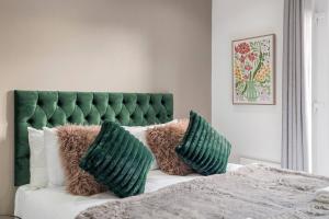 a bedroom with a green headboard and pillows on a bed at Cosy Studio Perfect For Two in Hanwell