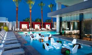 a hotel pool with white chairs and palm trees at Palms Place Hotel Magnificent Suite w/ Strip View (open Balcony) in Las Vegas