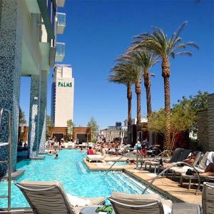 a pool with palm trees and people in a hotel at Palms Place Hotel Magnificent Suite w/ Strip View (open Balcony) in Las Vegas