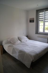 1 cama blanca en un dormitorio con ventana en La longère de Suzanne, en Arrest