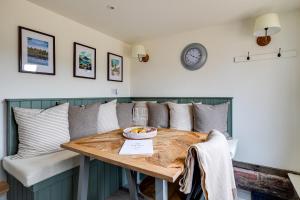 a dining room table with pillows and a clock on the wall at Oak Tree Hideaway in Whitchurch