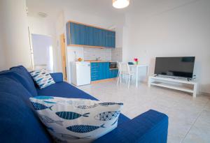 a living room with a blue couch and a kitchen at 1-bedroom 500m away from the beach in Kallithea Halkidikis