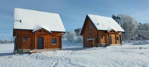 two wooden buildings are covered in snow at AB Domki Pstrążna in Kudowa-Zdrój