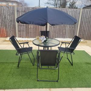 a table with two chairs and a blue umbrella at Exquisite 3-Bed Royal Pearl Home in Greater London in Thamesmead