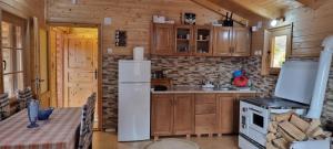 uma cozinha com armários de madeira e um frigorífico branco em Brvnara Gradišnjica em Andrijevica