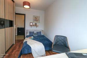 a bedroom with a blue bed and a chair at Apartament Działkowa przy Parku in Chorzów