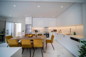 een keuken met een houten tafel en gele stoelen bij Imperial House - Hersonissos Center - Sleeps 8 in Chersonissos
