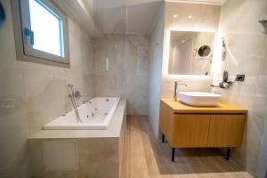 een badkamer met een wastafel, een bad en een spiegel bij Imperial House - Hersonissos Center - Sleeps 8 in Chersonissos