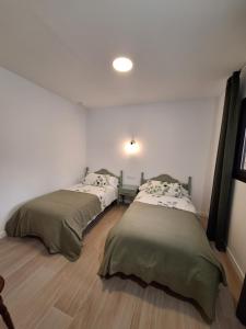2 łóżka w pokoju z białymi ścianami i drewnianą podłogą w obiekcie Casas Rurales Los Marqueses w mieście Valmuel
