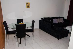 a living room with a glass table and black couch at Apartamento T2 Equipado e Aconchegante. in Praia