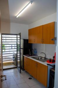 a kitchen with wooden cabinets and a stainless steel refrigerator at Apartamento T2 Equipado e Aconchegante. in Praia