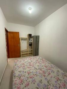 1 dormitorio con 1 cama con colcha de flores en Promoção especial do mês de março em Itanhaém en Itanhaém
