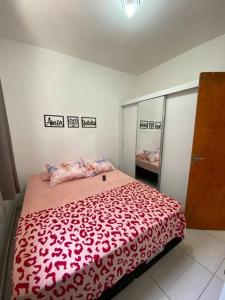 um quarto com uma cama grande e um cobertor vermelho em Promoção especial do mês de março em Itanhaém em Itanhaém
