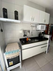 uma cozinha com armários brancos e um forno com placa de fogão em Promoção especial do mês de março em Itanhaém em Itanhaém