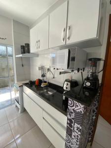 uma cozinha com armários brancos e um balcão preto em Promoção especial do mês de março em Itanhaém em Itanhaém