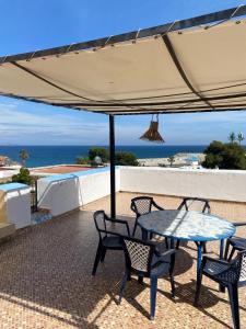 eine Terrasse mit einem Tisch und Stühlen unter einem Sonnenschirm in der Unterkunft Appartement vue sur mer Résidence Marsa M’diq in Mʼdik