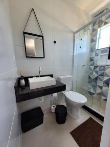 Un baño con lavabo, inodoro y espejo. en Eco Loft Brisa do Mar, en Cabo Frío