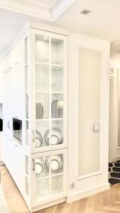 a white cabinet filled with plates and dishes at Apartament BIANCO Royal in Częstochowa