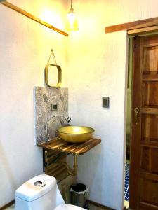 a bathroom with a gold bowl on a counter next to a toilet at Nativo Lodge Cabaña in Playas