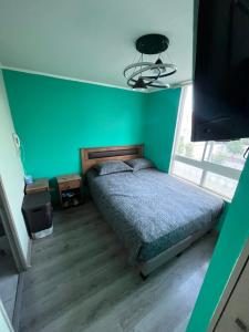sypialnia z łóżkiem i zieloną ścianą w obiekcie Departamento Avenida tobalaba w mieście Santiago