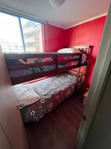 2 łóżka piętrowe w pokoju z czerwoną ścianą w obiekcie Departamento Avenida tobalaba w mieście Santiago