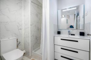 a white bathroom with a sink and a toilet at LA PERLE DU SUD : Classement officiel 3 étoiles + 2 Clés Clévacances in Frontignan +25 photos