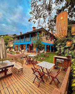 une terrasse en bois avec des tables et des chaises et un bâtiment dans l'établissement Pousada e Café Tangará, à Conceição da Ibitipoca