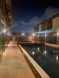 a building with a swimming pool at night at Bangalô em Corais de Carapibus in Conde