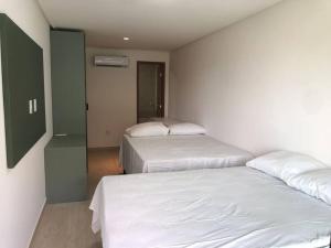 two beds in a room with white sheets at Bangalô em Corais de Carapibus in Conde