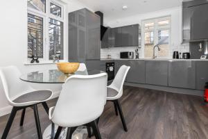 a kitchen with a glass table and white chairs at Outstanding 2 Bed Apartment in Central Camden Sleeps 6 in London