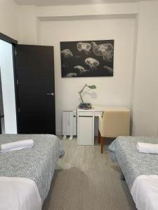 a bedroom with two beds and a desk with a lamp at Despertar in Antequera
