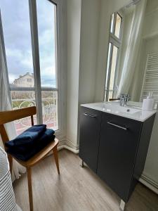La salle de bains est pourvue d'un lavabo, d'un miroir et d'une fenêtre. dans l'établissement Sunny Apt on D-Day Beach with Parking, à Saint-Côme-de-Fresné