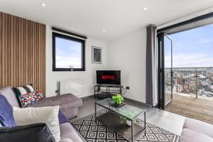 een woonkamer met een bank en een tv bij Beautiful Chelmsford Penthouse with Balcony in Chelmsford