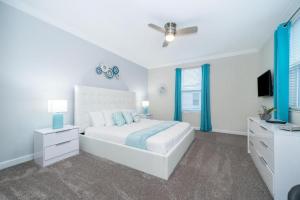 a white bedroom with a bed and a ceiling fan at Fabulous Villas 5 minutes away from Disney! in Kissimmee