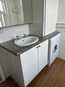 a bathroom with a sink and a washing machine at 120 Mortimer St, Herne Bay in Kent