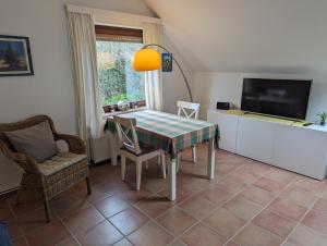 comedor con mesa, sillas y TV en FeWo Deichblick - Javenloch, en Wittmund