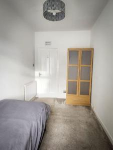 een slaapkamer met een bed en een houten deur bij Central 2-bedroom bunglow with double sofa bed in Carnoustie