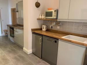 a kitchen with a sink and a microwave at The Barn at White Rose Cottage in Towcester