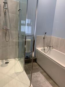 a bathroom with a shower and a tub and a sink at The Barn at White Rose Cottage in Towcester