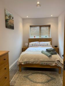 a bedroom with a bed with a dresser and a window at The Barn at White Rose Cottage in Towcester