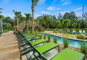 a row of green lounge chairs by a pool at a resort at Fabulous Villas 5 minutes away from Disney! in Kissimmee