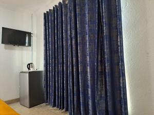 a blue curtain in a room with a television at Riverside guesthouse in Phalaborwa