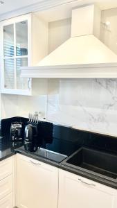 a kitchen with white cabinets and a sink at Apartament BIANCO Royal in Częstochowa