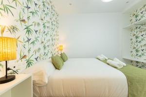 1 dormitorio con cama blanca y papel pintado tropical en New! La Casa del cerrajero, en Sevilla