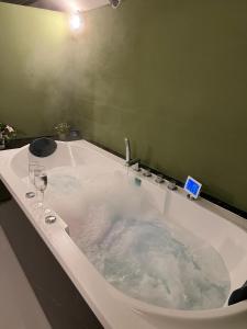 a bath tub with two glasses of wine in it at Charmante Art Deco rijwoning in Ostend