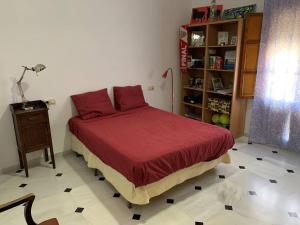 een slaapkamer met een bed met rode lakens en een tafel bij Casa Rural Oropesa in Villanueva del Ariscal